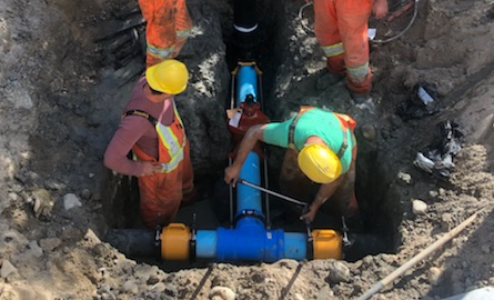 construction workers digging in a hole to work on water pipes